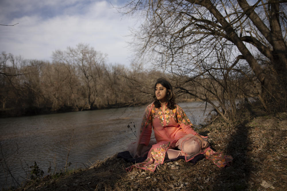 Maansi sits on a riverbank along Brandywine River in Delaware in winter 2020, wearing a traditional Indian salwar kurta.