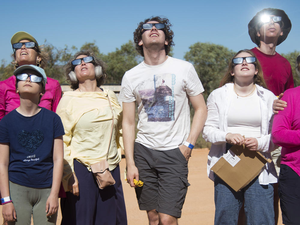 People wear protective glasses as they look up at a solar eclipse in Exmouth, Australia, Thursday, April 20, 2023.