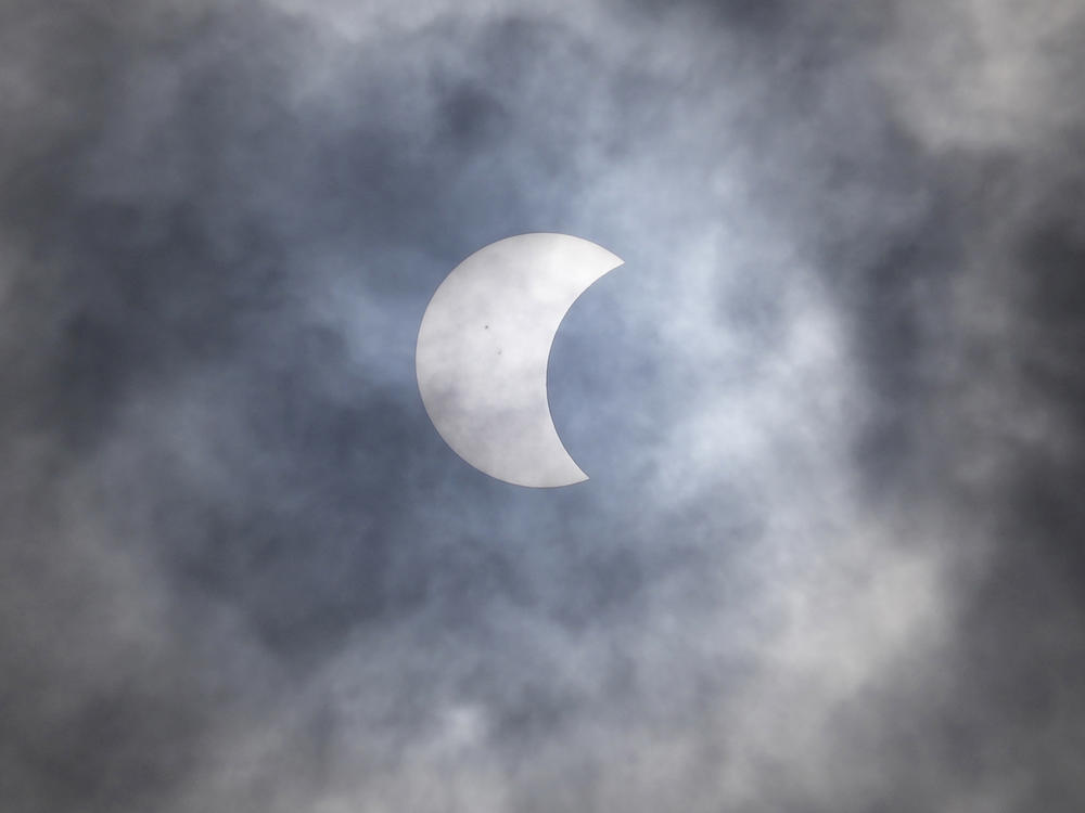 A partial solar eclipse is seen through the cloud over Jakarta, Indonesia, Thursday, April 20, 2023.