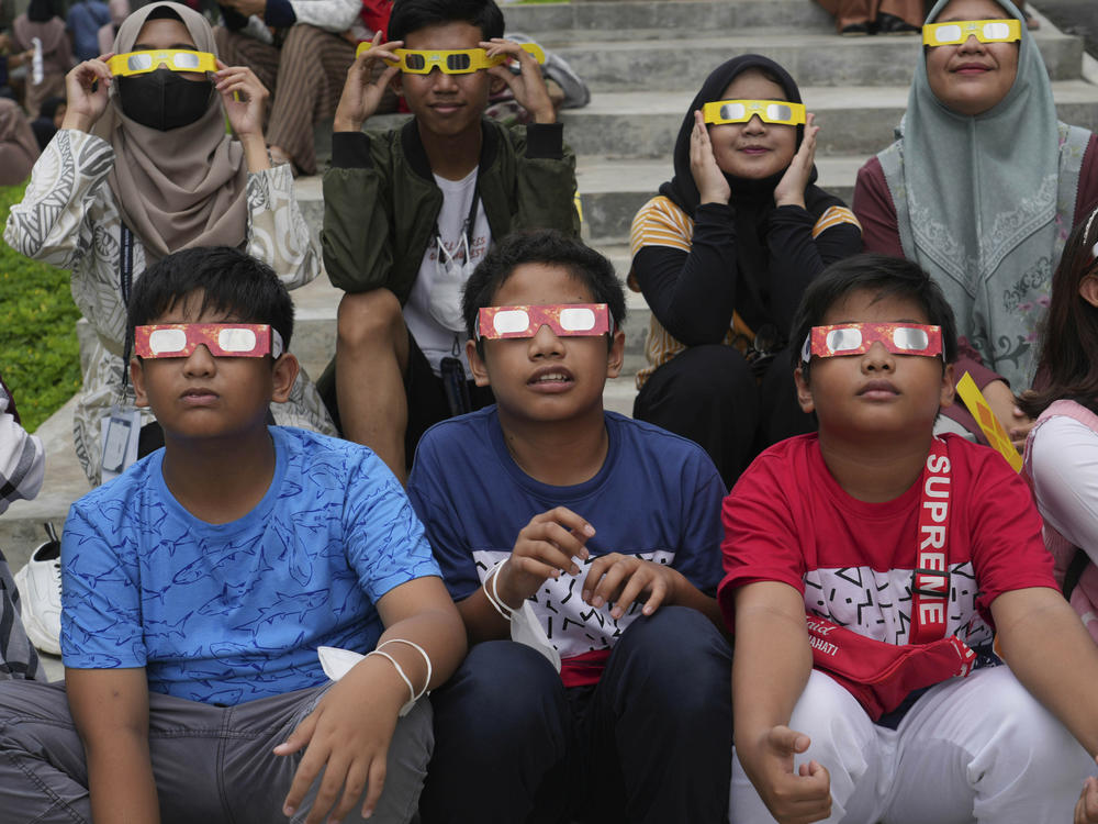 Indonesian youths wear protective glasses to watch solar eclipse in Jakarta, Indonesia, Thursday, April 20, 2023.