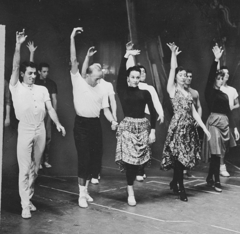 Chita Rivera, center, in rehearsal for <em>West Side Story</em> beside choreographer Jerome Robbins in July 1957.