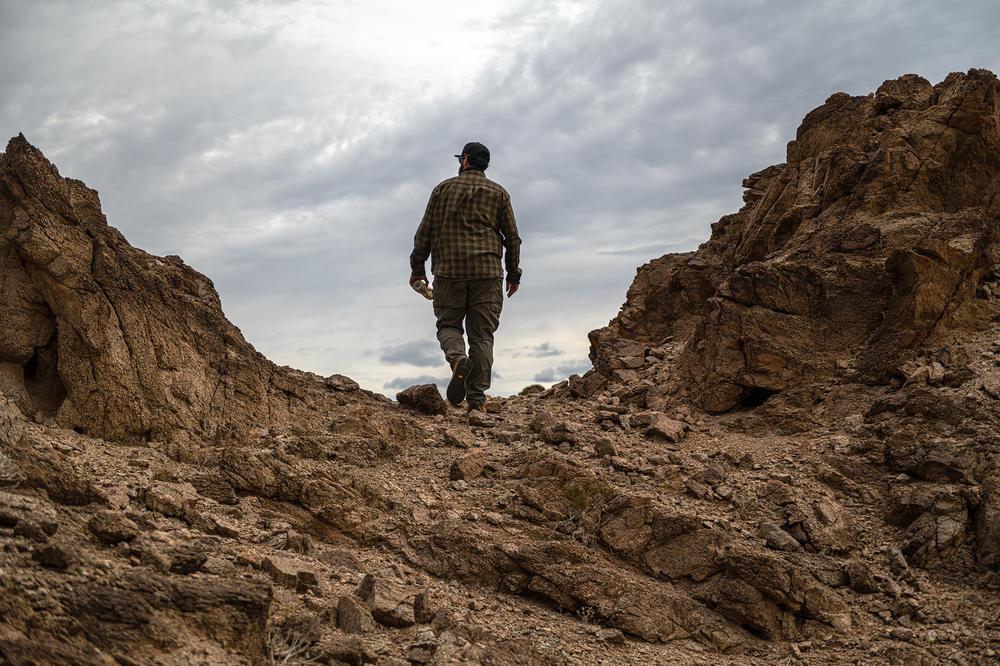 James Cordero hikes through a canyon he suspects migrants move through on their way north after crossing the U.S.-Mexico border.