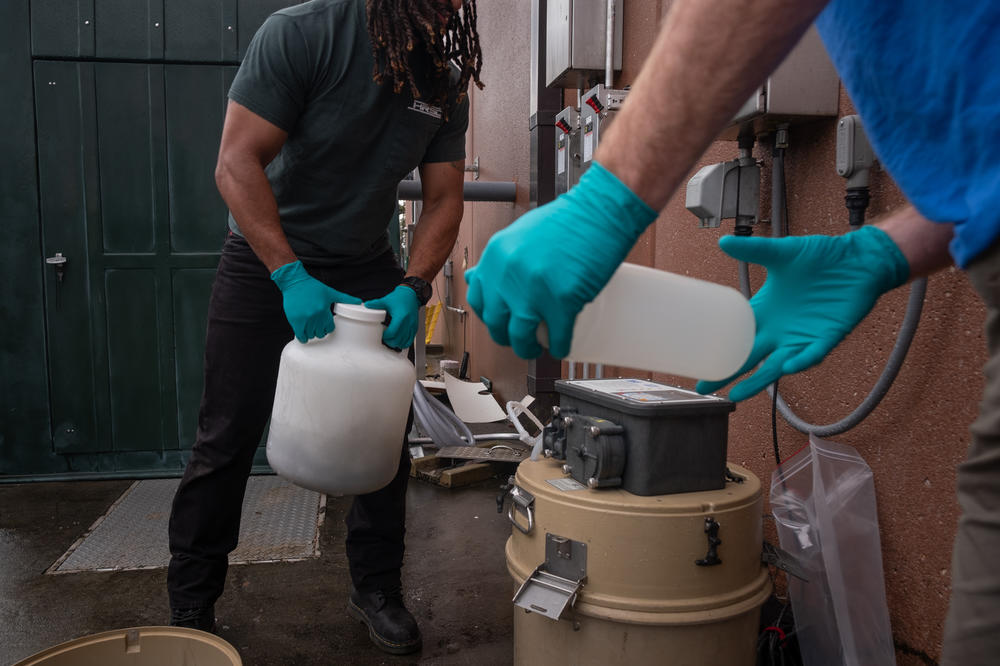 Marcos Davila-Banrey and Jon Nelson prepare to capture a wastewater sample for the Hampton Roads Sanitation District COVID surveillance program.
