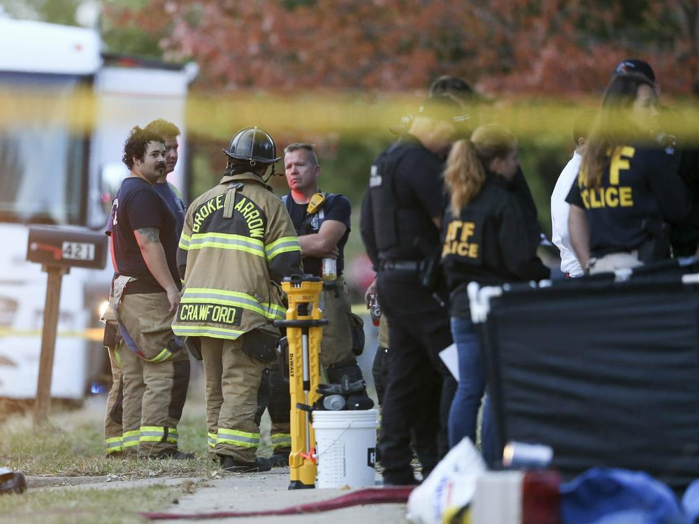 Police and firefighters investigate the scene of a house fire where eight people were found dead in Broken Arrow, Okla., on Oct. 27, 2022.