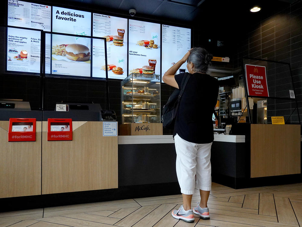 A customer waits to order food at a Miami McDonald's on July 26, 2022. The CEO of McDonald's expects the U.S. to experience a mild recession and says customers have grown more reluctant to splurge on or supersize their orders.