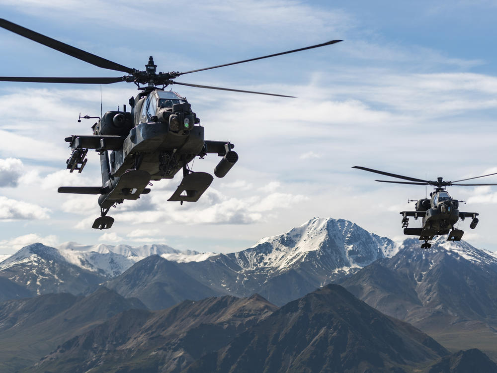 In this photo released by the U.S. Army, AH-64D Apache Longbow attack helicopters from the 1st Attack Battalion, 25th Aviation Regiment, fly over a mountain range near Fort Wainwright, Alaska, on June 3, 2019. The U.S. Army says two helicopters similar to these crashed on Thursday near Healy, Alaska, killing three soldiers and injuring a fourth.