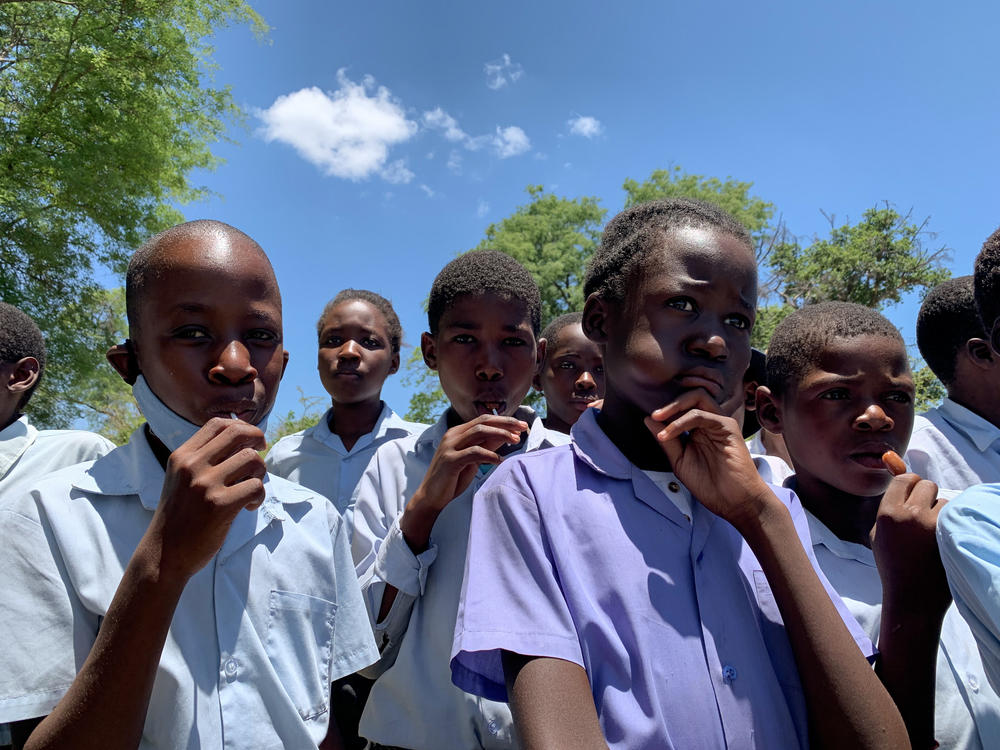The children enjoy lollipops as they listen to Mogalakwe describe cool features of the elephant, like the finger-like projection on its trunk and how its ears are shaped like the map of Africa.