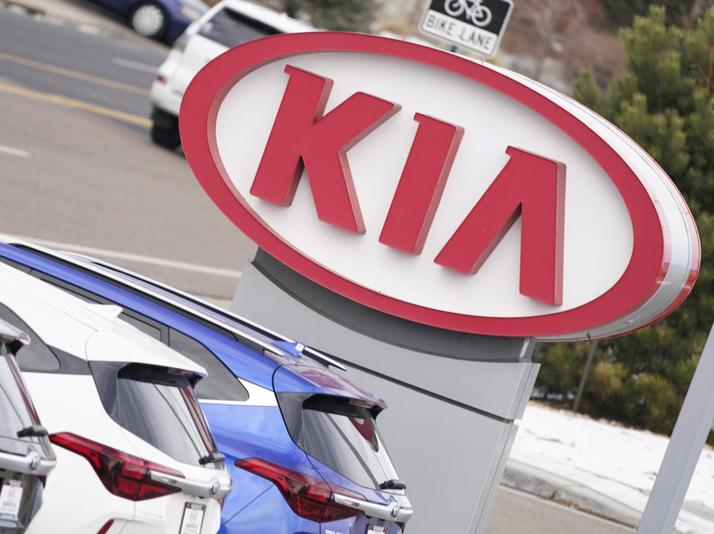 A Kia sign hangs over a row of unsold 2021 Seltos models in December 2020 at a dealership in Centennial, Colo.