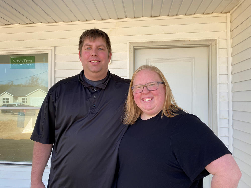 Cook employees Ryan and Shelby Bixler stand in front of the house they're buying from the company. They say they never could have afforded a new place like this at the full market price.