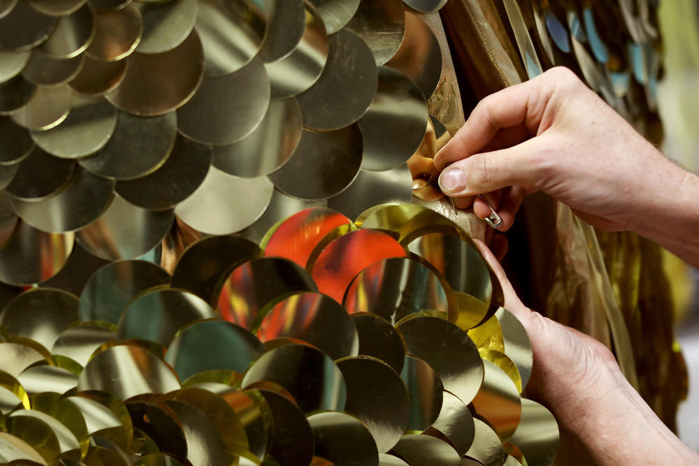 Costume designer Matthew Flower, who goes by Machine Dazzle, adjusts a gold cape worn by Belgian tenor <a href=