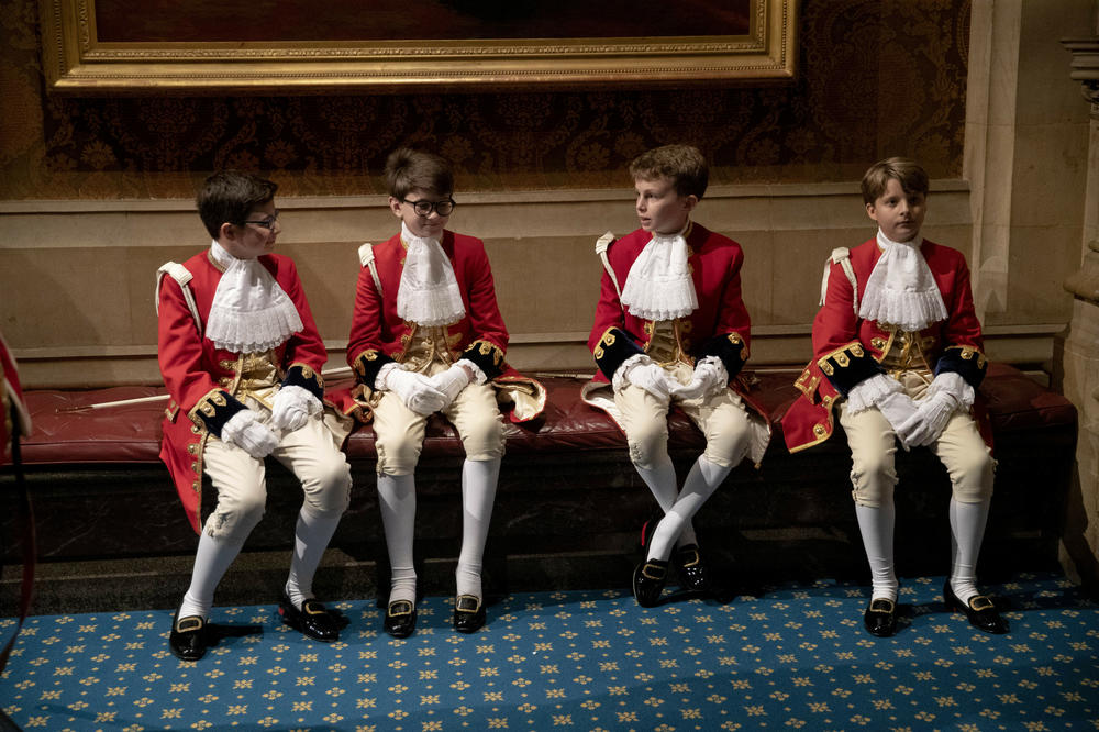 Page boys sit together before lining up for the arrival of Queen Elizabeth II at the Palace of Westminster for the State Opening of Parliament on Oct. 14, 2019.