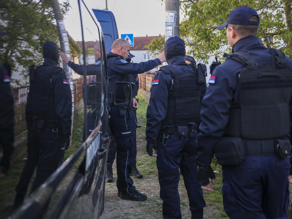 Police officers prepare for a chase in the village of Dubona, some 50 kilometers (30 miles) south of Belgrade, Serbia, Friday, May 5, 2023, near the scene of a Thursday night attack.