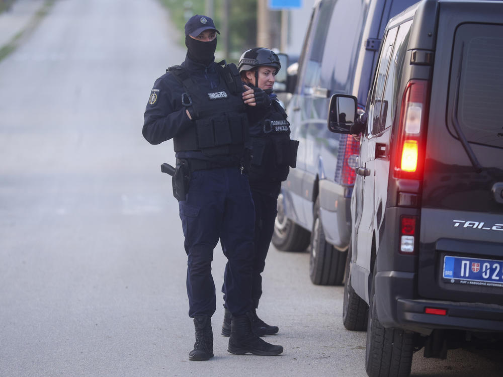 Police officers stand guard on a road in the village of Dubona, some 50 kilometers (30 miles) south of Belgrade, Serbia, Friday, May 5, 2023, as they block the road near the scene of a Thursday night attack.