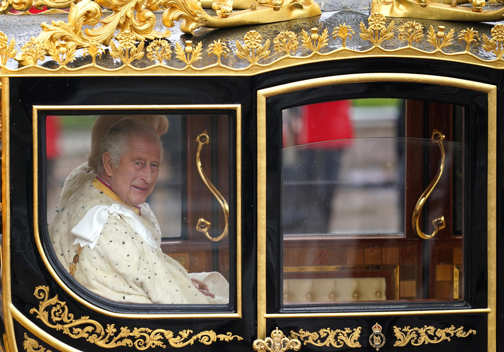 King Charles III and Queen Camilla are carried in the Diamond Jubilee State Coach as the King's Procession passes along The Mall to their coronation ceremony London.