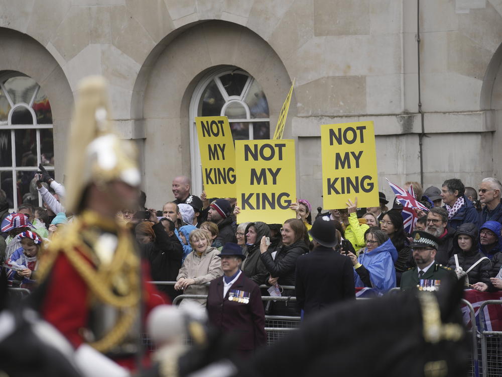 The procession accompanying Britain's King Charles III and Queen Camilla towards Buckingham Palace moves past anti-monarchist demonstrators on Saturday in London.
