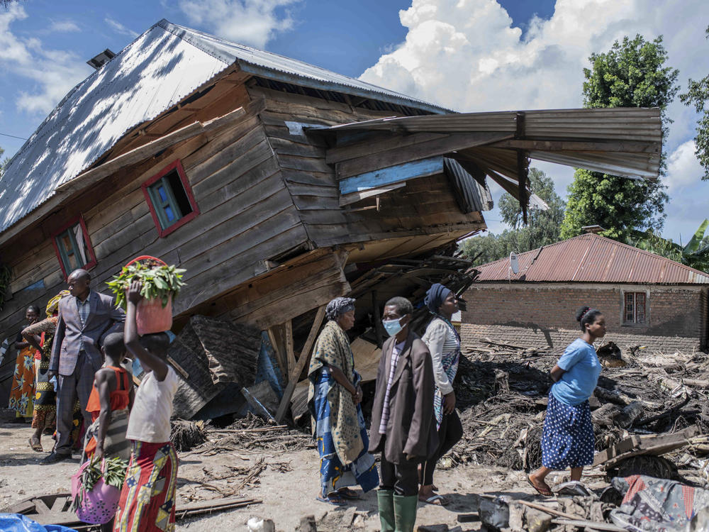 People walk next to a house destroyed by the floods in the village of Nyamukubi, South Kivu province, in Congo, Saturday, May 6, 2023. The death toll from flash floods and landslides in eastern Congo has risen according to the governor and authorities in the country's South Kivu province.