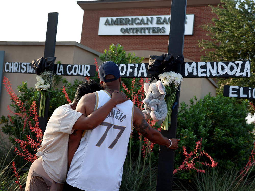 Robert Jackson and his mother, Cheryl Jackson, hug Monday as they visit a memorial near the scene of a mass shooting at the Allen Premium Outlets mall in Allen, Texas.