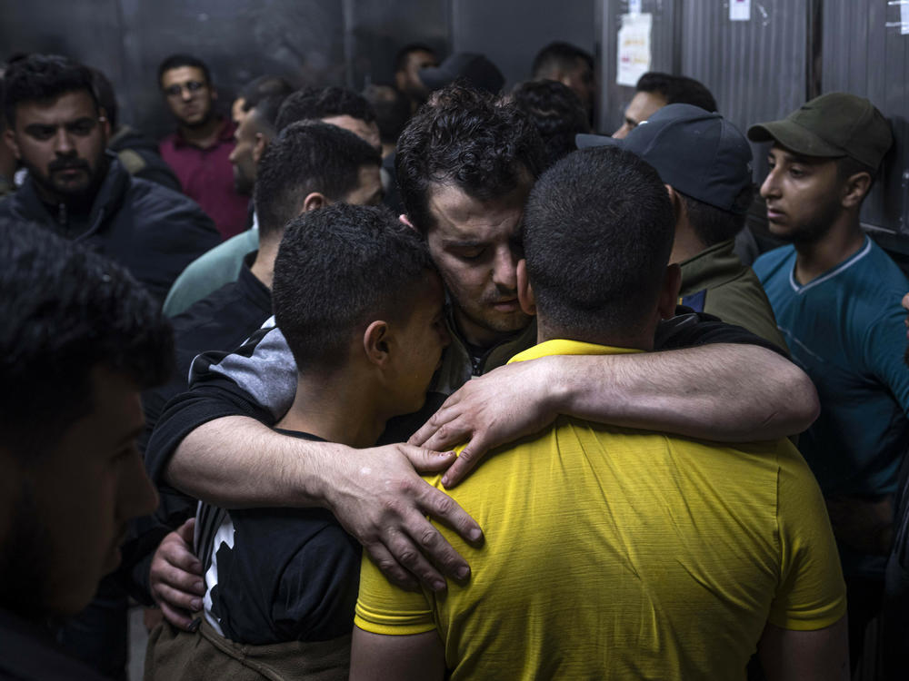Mourners comfort each other in the morgue of Al-Shifa Hospital after Israeli airstrikes killed a dozen Palestinians in Gaza City, Tuesday, May 9, 2023.