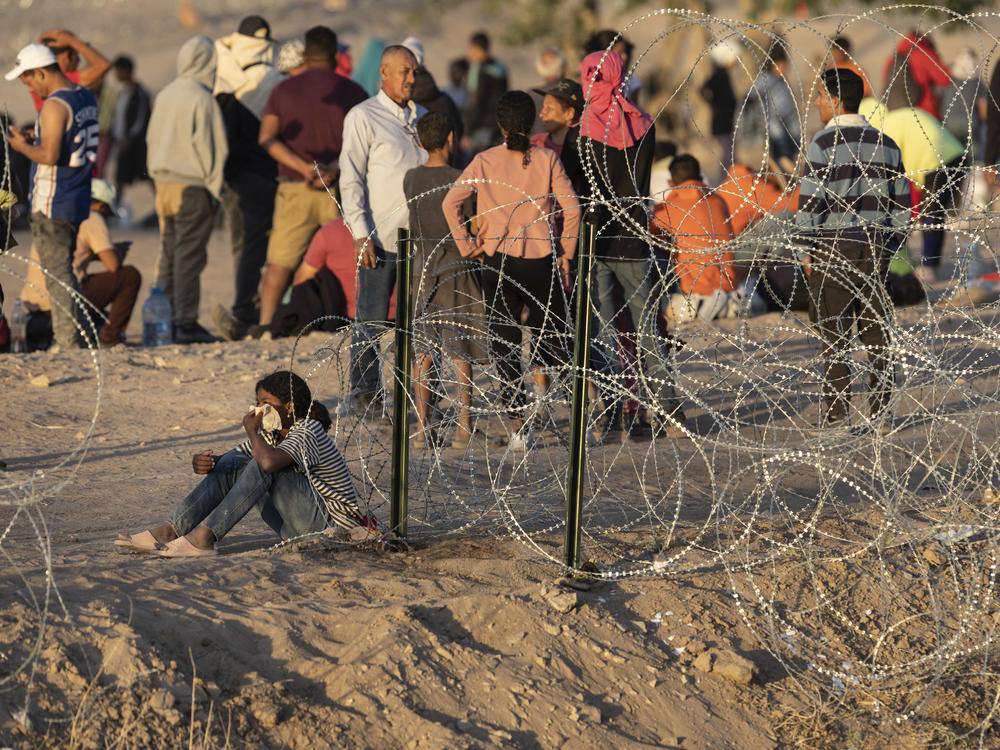 Immigrants wait near the U.S.-Mexico border fence this week in El Paso, Texas. The city has declared a state of emergency to access federal funding to house and feed the droves of new arrivals expected with the end of Title 42.