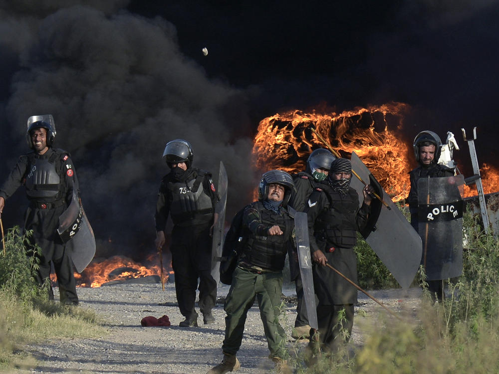 Police officers throw stones toward supporters of Pakistan's former Prime Minister Imran Khan during clashes in Islamabad on Wednesday. Khan's arrest on Tuesday sparked violence in major cities. On Thursday, the Supreme Court ordered Khan's release.