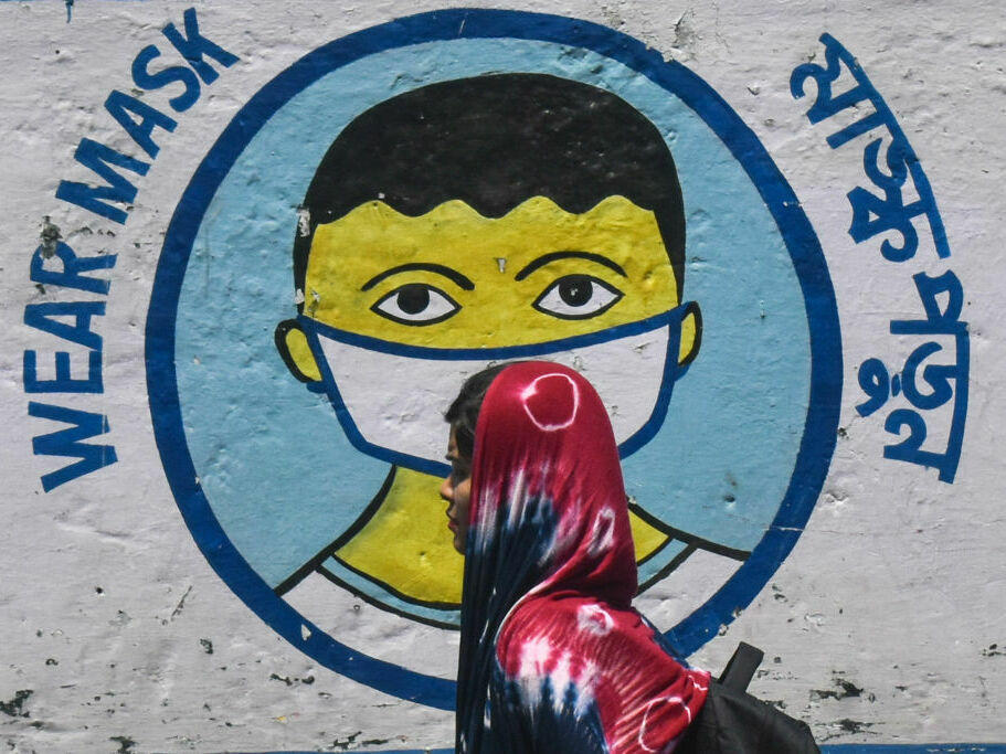 A poster in Kolkata, India, from peak pandemic days sends a message to mask up. Now that the official COVID-19 global emergency is no longer in effect, some folks are thrilled to stop masking — but others wonder if it's a good idea to keep up certain precautions.