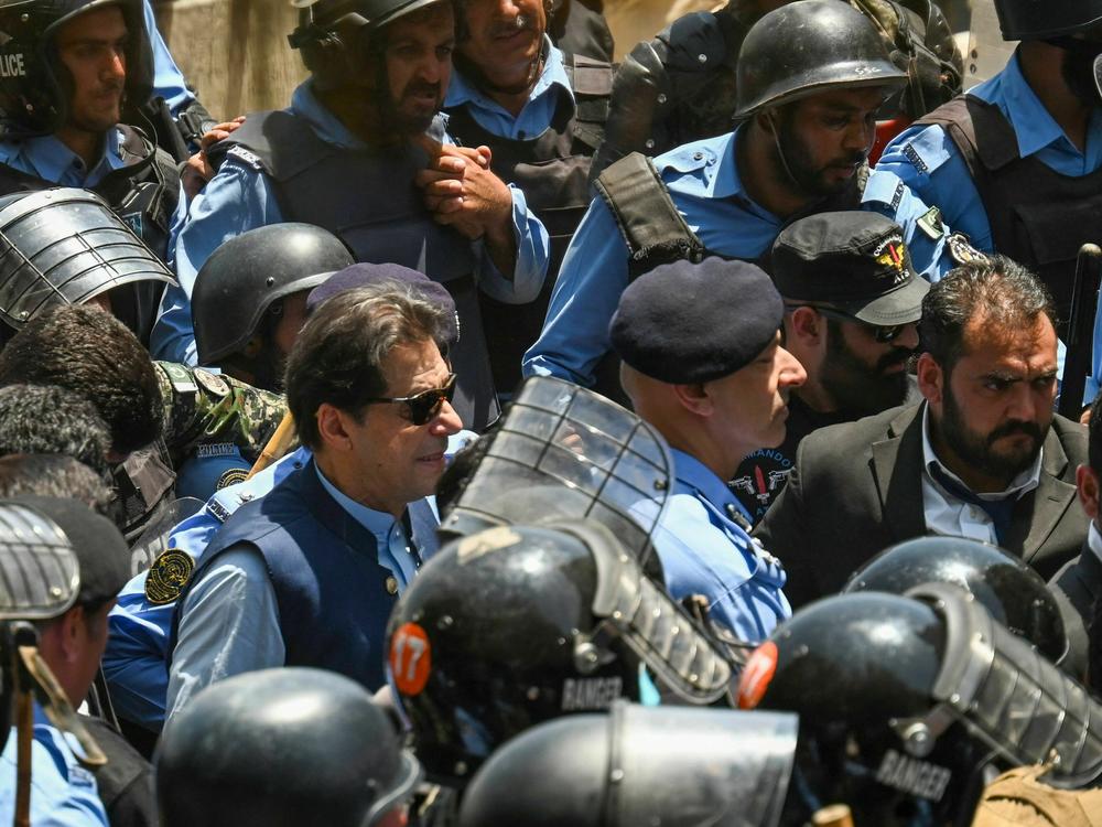 Policemen escort Pakistan's former Prime Minister Imran Khan as he arrives at the high court in Islamabad on Friday.