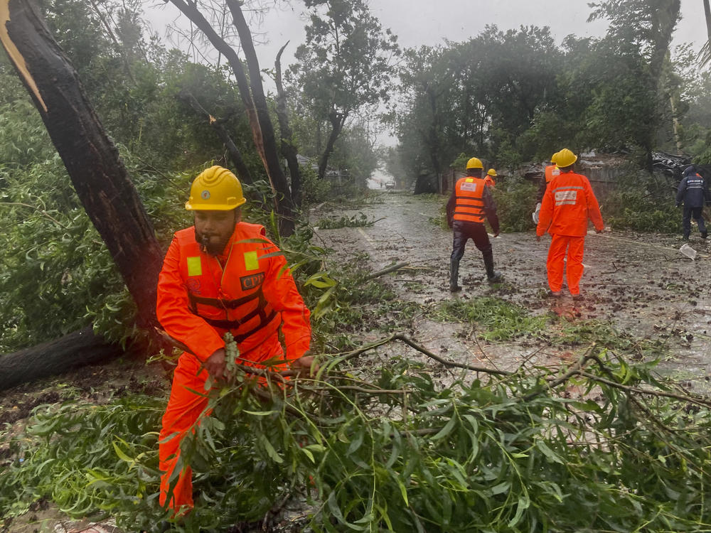 Rescue workers remove the fallen tress after a storm in Teknaf, near Cox's Bazar, Bangladesh, Sunday, May 14, 2023. Bangladesh and Myanmar braced Sunday as a severe cyclone started to hit coastal areas and authorities urged thousands of people in both countries to seek shelter.
