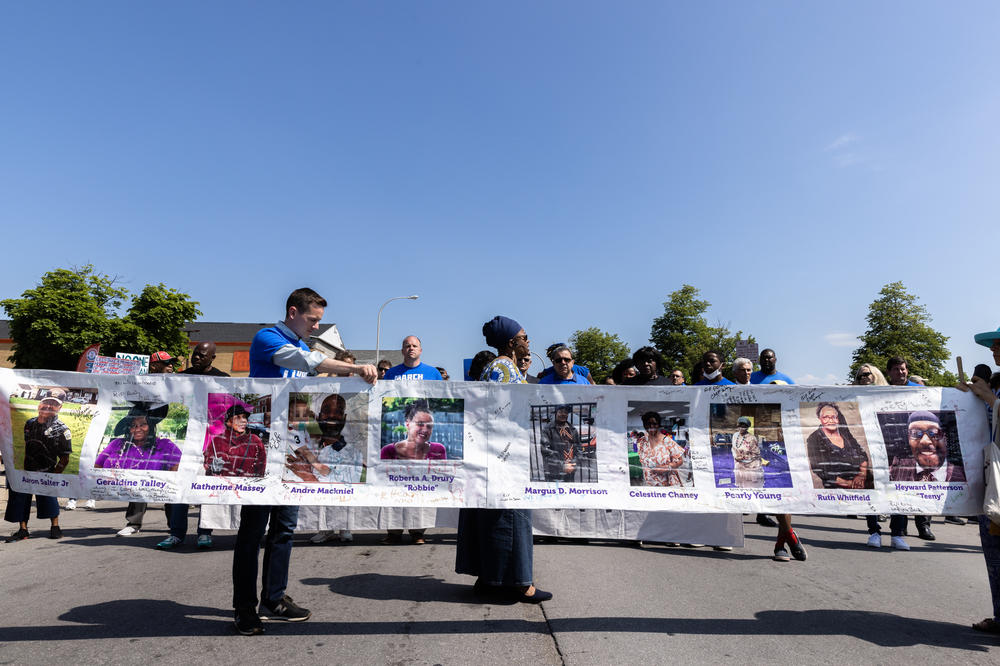 People participating in a March For Our Lives event pause at a memorial to the dead at Tops supermarket on June 11, 2022.