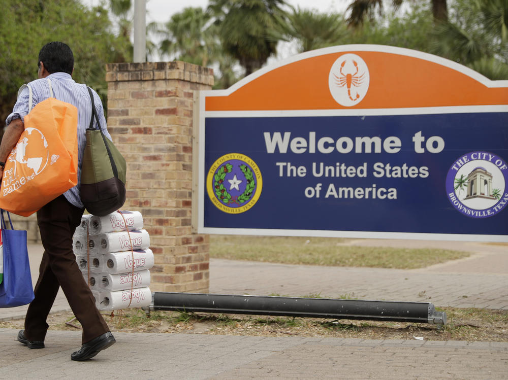 A pedestrian carries supplies as he enters Texas after crossing over from Mexico at the Gateway International Bridge on March 20, 2020, in Brownsville.