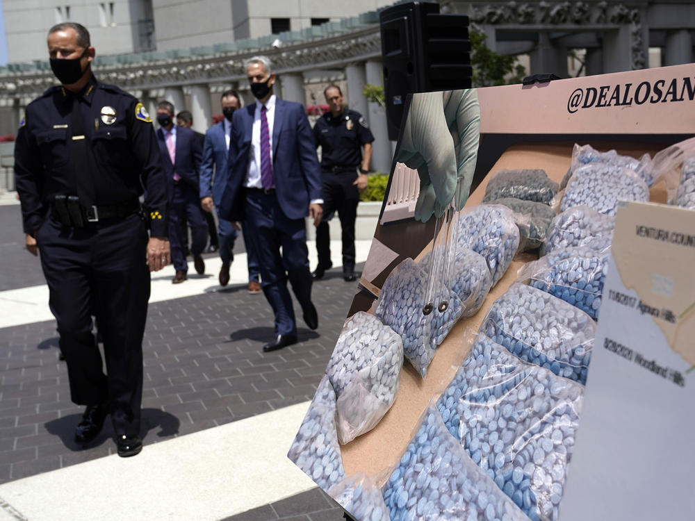 Officials walk past images of illegal drugs outside the Edward R. Roybal Federal Building on May 13, 2021, in Los Angeles.