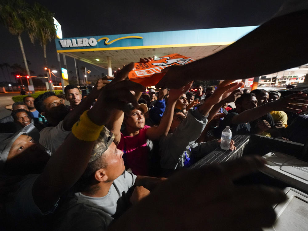 Migrants receive pizza from volunteers after being released from a respite center at the Texas-Mexico border on May 11 in Brownsville.