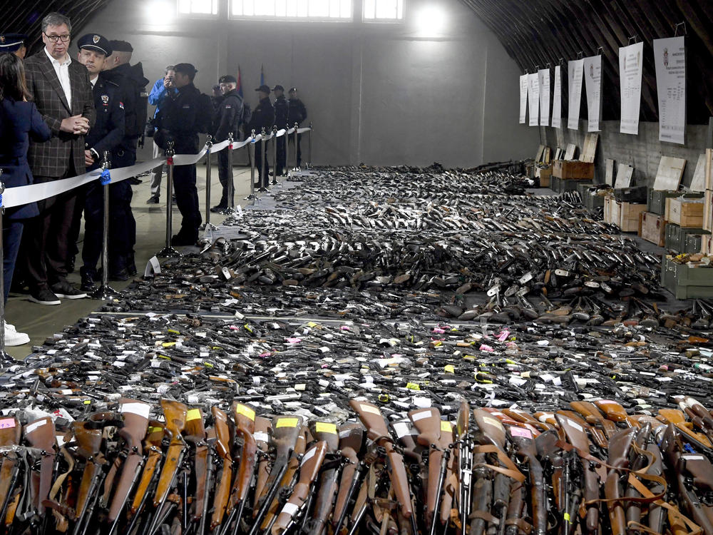 In this photo provided by the Serbian Presidential Press Service, Serbian President Aleksandar Vucic, left, inspects weapons collected as part of an amnesty near the city of Smederevo, Serbia, Sunday, May 14, 2023.