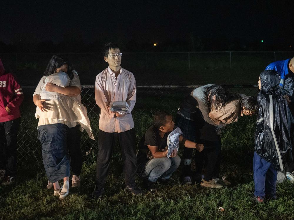 Migrants try to stay warm as they wait in the rain after turning themselves over to U.S. Border Patrol agents after crossing over from Mexico in Fronton, Texas on May 12.