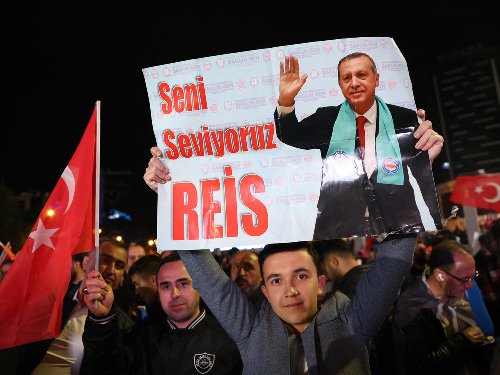 A supporter of Turkish President Tayyip Erdogan holds a poster which reads 