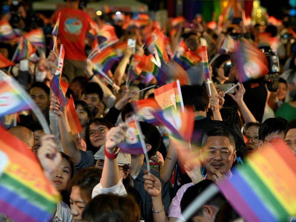 People wave rainbow flags during a mass wedding banquet for gay couples in front of the Presidential Palace in Taipei in 2019. Taiwan legalized gay marriage in 2019. But until now, those married couples could only adopt children related to one of the partners.