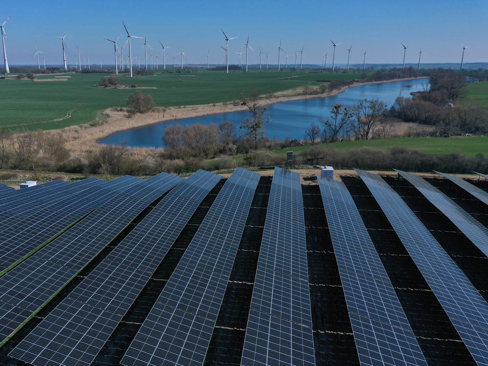 Newly installed solar panels face the sky at the construction site of a new solar energy park as wind turbines spin behind last month near Prenzlau, Germany.
