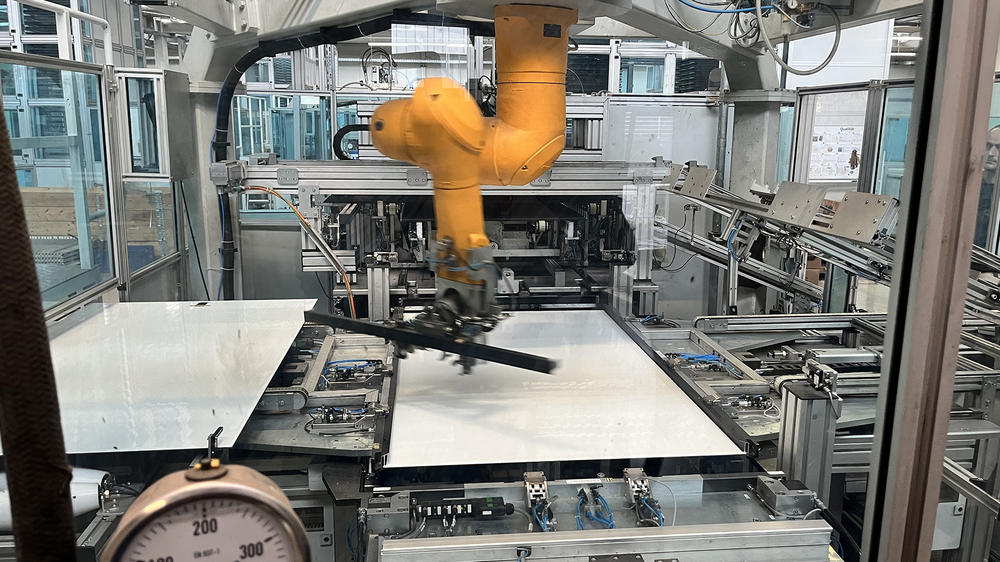 A robotic arm affixes photovoltaic cells onto tempered glass at the Heckert Solar assembly line in Chemnitz, Germany.