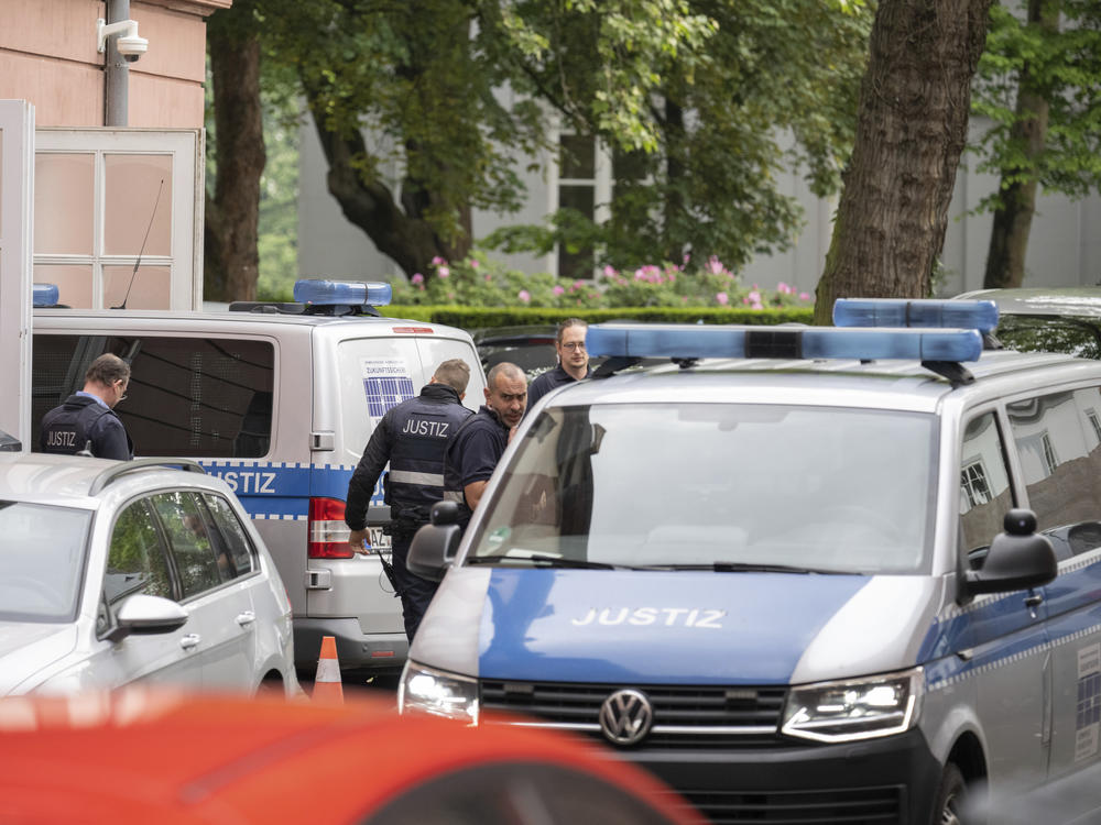 Two judiciary vans, each carrying defendants, drive in a courtyard before the start of the trial against members of the 
