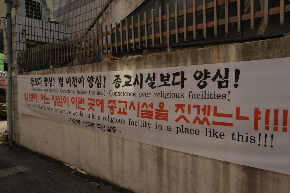 A banner hung in the alleyway across from the Dar ul Emaan Kyungpook Islamic Center.