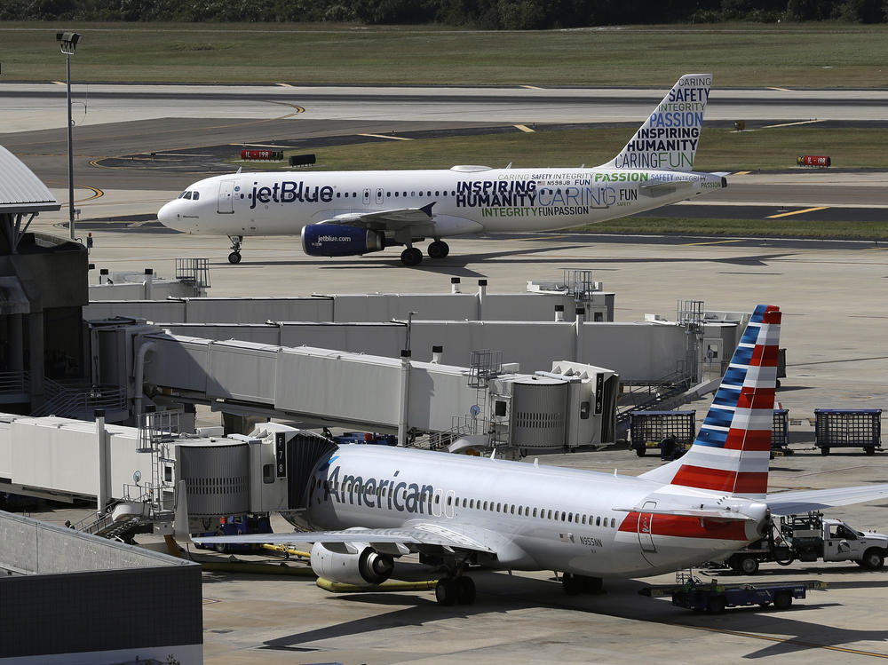 A JetBlue Airbus A320 taxis to a gate on Oct. 26, 2016, after landing, as an American Airlines jet is seen parked at its gate at Tampa International Airport in Tampa, Fla.