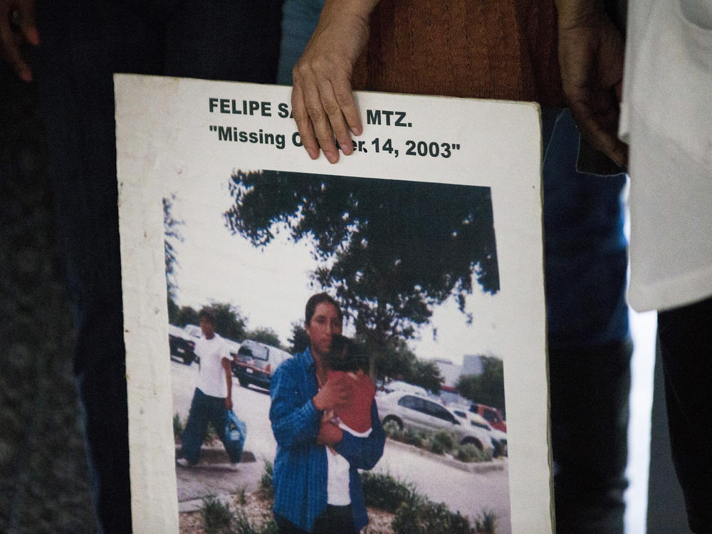 A woman holds a sign for Felipe Santos during a remembrance ceremony for missing persons at Cambier Park in Naples on Oct. 25, 2017.