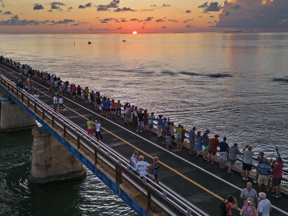 In this aerial photo provided by the Florida Keys News Bureau, attendees watch and toast the sunset at a Florida Keys bicentennial celebration, Friday, May 19, 2023, on the restored Old Seven Mile Bridge in Marathon, Fla.