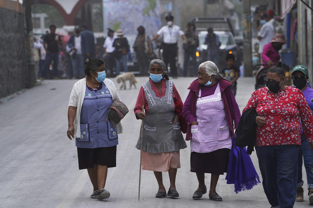 Women walk on the ash-covered streets Monday in Santiago Xalitzintla.