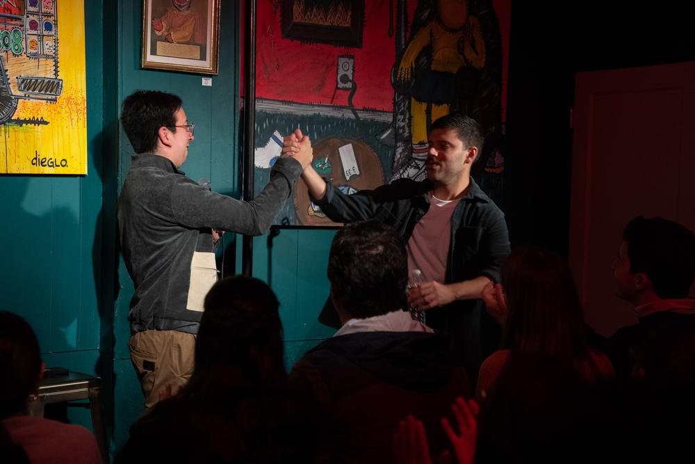 Fellow performer Daniel Castañeda, left, welcomes Colina to the stage.