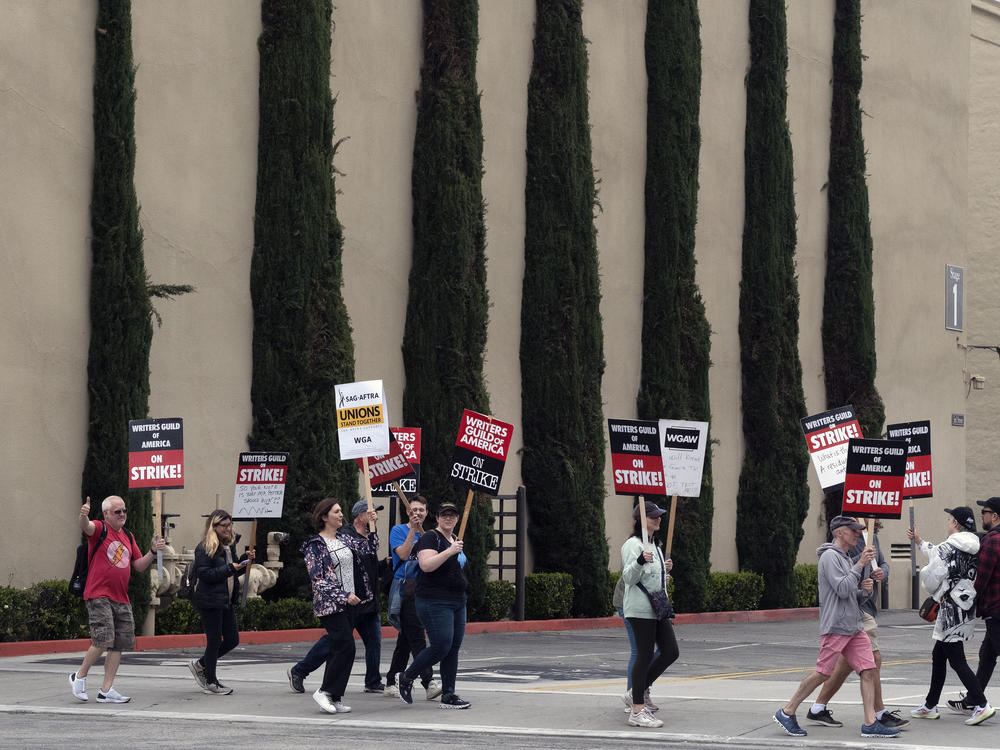 Picketers pass near stage 5 at a studio entrance during a Writers Guild rally outside Warner Bros. Studios, on Wednesday, in Burbank, Calif.