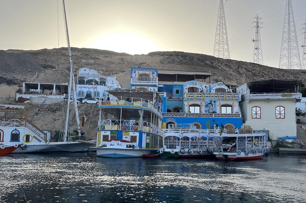 Boats are docked along the banks of the Nile Rive in Aswan, Egypt. Colorful homes with domed roofs are characteristic of Nubian culture, which spans this part of Egypt and across the border into northern Sudan. May 6, 2023.