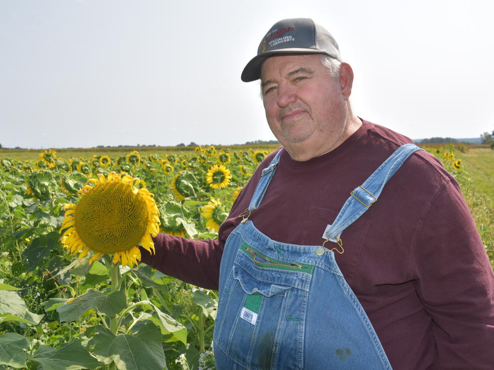 Brandt shown with a sunflower, one of the plants he used as crop cover to help boost soil health.