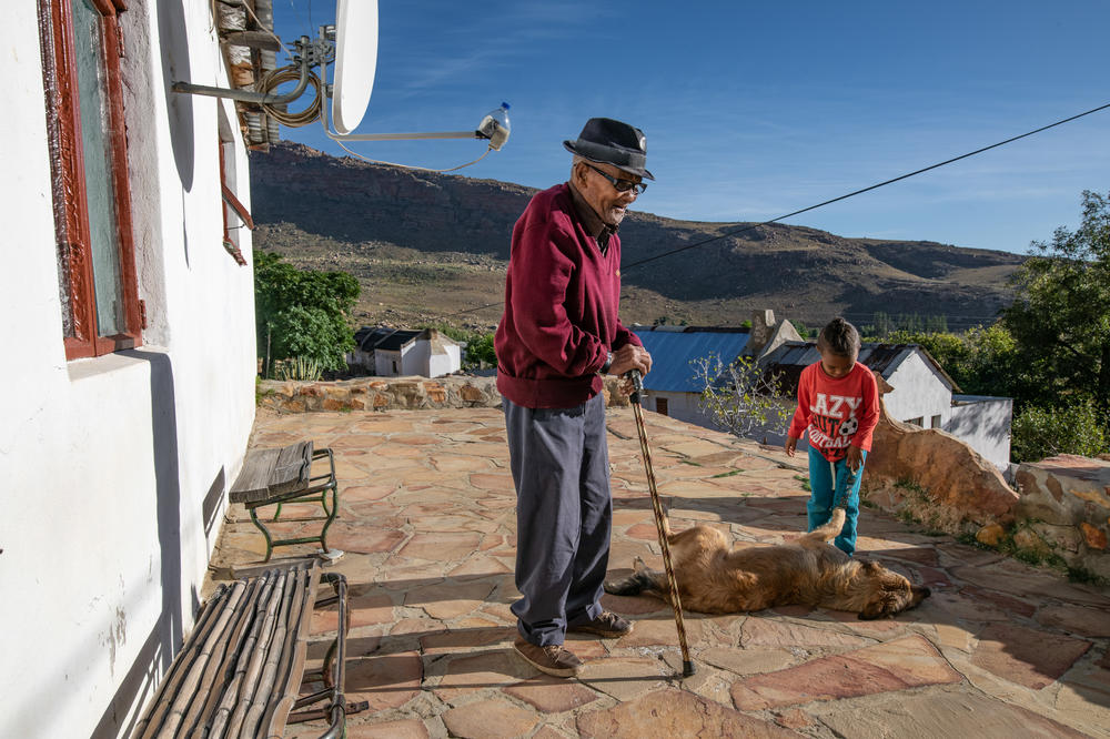 Oom Kosie Salomo, 89, an Indigenous Khoisan rooibos farmer and one of the first people in the area to start cultivating the crop, photographed on the porch of his home with his great grandson in the village of Langkloof, South Africa.