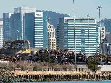 Downtown Oakland can be seen behind piles of scrap metal at a manufacturing facility at the Port of Oakland on March 8, 2022.