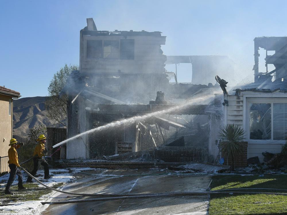Firefighters hose down a burning house during the Tick Fire in Agua Dulce near Santa Clarita, Calif., in October 2019.